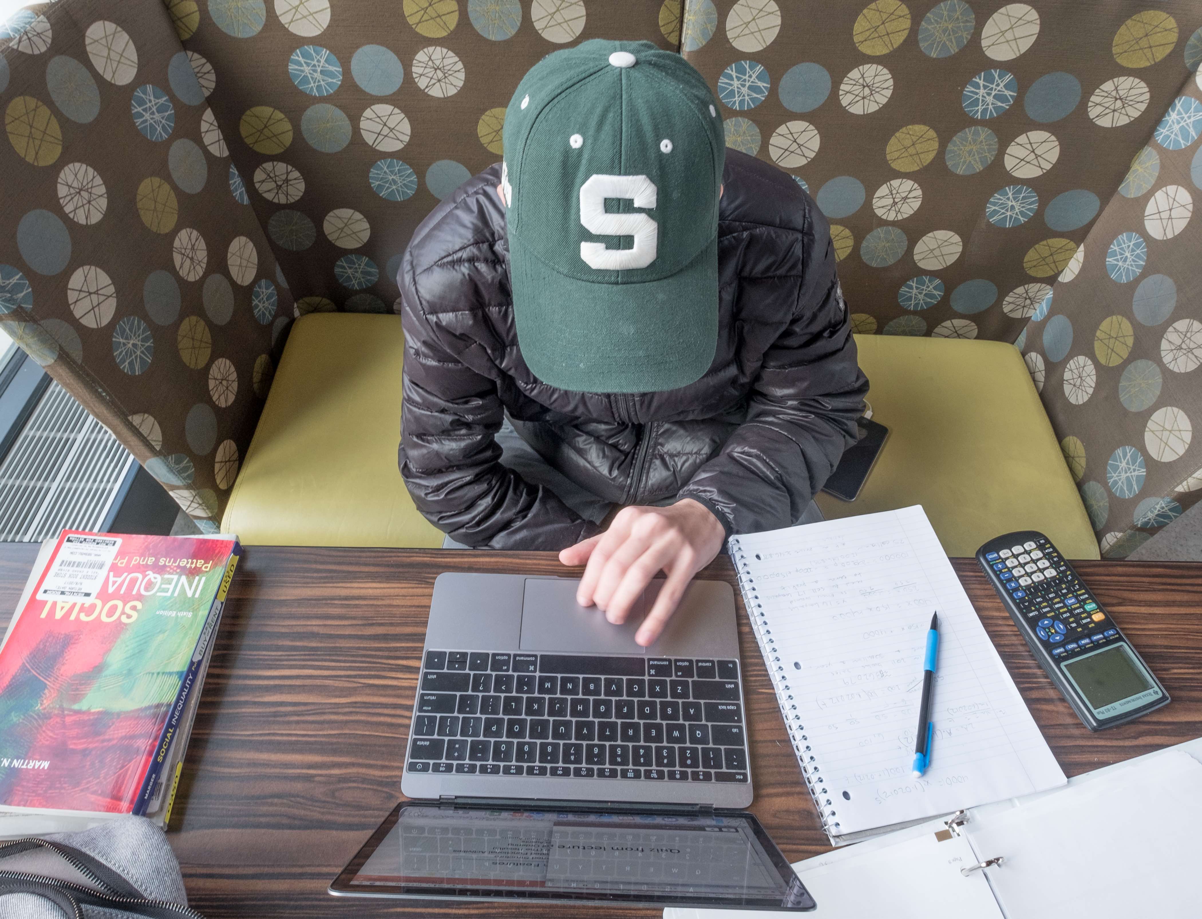 student with MSU hat on computer